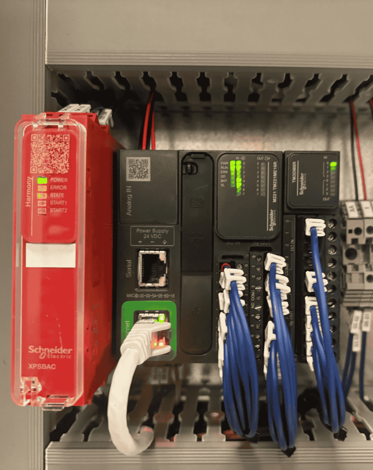 Matériel électrique industriel : module de sécurité Schneider Electric, alimentation 24VDC et automates programmables câblés dans une armoire électrique